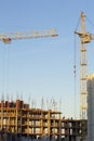 Tower crane on the construction of a building with a frame of reinforced concrete. Flooded by the light of the setting sun. Royalty Free Stock Photo