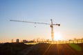 Tower crane at construction site on sunset background. Construction crane constructing a new residential building. Royalty Free Stock Photo