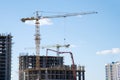 Tower crane lifting a concrete bucket at construction site. Workers during formworks and pouring concrete through a ÃÂoncrete pump