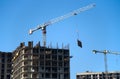 Tower crane lifts the block for building under construction at background blue sky at sunny day. Precast concrete  slab hanging Royalty Free Stock Photo