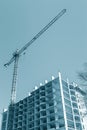 Tower crane near apartment building under construction against blue sky background Royalty Free Stock Photo