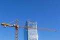 Tower crane next to a modern business center against the blue cloudy sky. Royalty Free Stock Photo