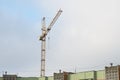 Tower crane over roof house against sky.