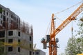 A tower crane among a thicket of trees and buildings during the construction of a large residential complex. Real estate