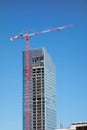 Tower crane on top of construction skyscraper building over blue sky