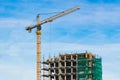 Tower crane and unfinished house against the blue sky. Construction site. Building. Royalty Free Stock Photo