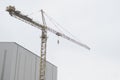 Tower crane yellow tall high in sky over building site and factory