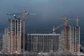 Tower cranes building a new tall apartment building at a construction site in the city during the day. Profitable investments and Royalty Free Stock Photo