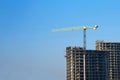Tower cranes constructing a new residential building at a construction site against blue sky. Renovation program, development, Royalty Free Stock Photo