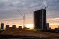 Tower cranes at construction site on sunset background. Construction crane constructing a new residential building Royalty Free Stock Photo