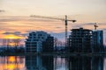 Tower cranes and high residential apartment buildings under construction on lake shore. Real estate development Royalty Free Stock Photo