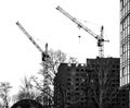 Tower cranes next to an unfinished multi-story building. Urban background with construction site