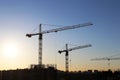 Tower cranes and unfinished residential buildings on sunrise background