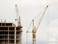 Tower cranes work during the construction of a multi-story building. New apartments for residents and premises for offices. Risky