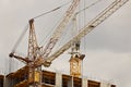 Tower cranes work during the construction of a multi-story building. New apartments for residents and premises for offices. Risky Royalty Free Stock Photo