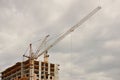 Tower cranes work during the construction of a multi-story building. New apartments for residents and premises for offices. Risky