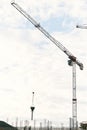 Tower cranes work at the construction site of a multi-storey building against the background of a blue sky with white Royalty Free Stock Photo