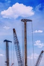 Tower cranes works on construction site against the backdrop of fluffy clouds Royalty Free Stock Photo