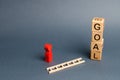 tower of cubes with an inscription goal and a red figure of a man stands near fallen ladder. concept of achieving the goal