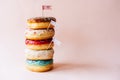 A tower of delicious glazed cream donuts on a pastel pink background