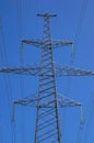 Tower with high-voltage energy transmission wires against the blue sky. Royalty Free Stock Photo