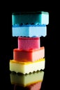 Tower of kitchen sponges for washing dishes. Green, blue, pink, orange and yellow sponge on a black background, isolate. Royalty Free Stock Photo