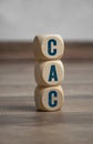 Tower made of cubes and dice with acronym CAC customer acquisition cost on wooden background Royalty Free Stock Photo