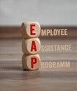 Tower made of cubes, dice or blocks with acronym EAP Employee Assistance Program on wooden background