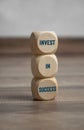 Tower made of cubes and dice showing the message invest in success on wooden background Royalty Free Stock Photo