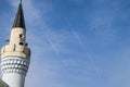 tower of the minaret of the mosque against the blue sky and the contrail from aircraft Royalty Free Stock Photo