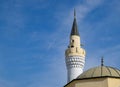 tower of the minaret of the mosque against the blue sky and the contrail from aircraft Royalty Free Stock Photo