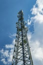 A tower for mobile communication antennas against a blue sky with white clouds. Royalty Free Stock Photo