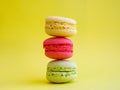 tower of multi-colored assorted bright macarons close-up on yellow background