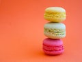 tower of multi-colored assorted bright macaroons close-up, on orange background