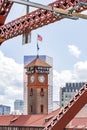 The tower of the old railway station against the backdrop of a modern skyscraper through the trusses of the Broadway bridge in Royalty Free Stock Photo