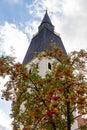 Tower of the parish church of St. Lorenz in Berching, Bavaria in autumn with multicolored tree in foreground