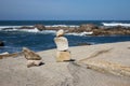 Tower of small stones on ocean coast with rocks on background. Seascape with stone art. Balance and harmony concept.