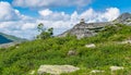 Tower of stones on a green hill blue sky white fluffy clouds. The concept of extreme outdoor recreation ecotourism. Royalty Free Stock Photo