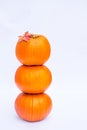 Tower of Three stacked mini pumpkins with fall maple leaf on the top on the white background isolated. Autumn holiday, harvest, He