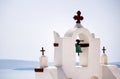 A tower top of a church with cross sign and bells architecture located in oia village in one of Cycladic island in Santorini, Royalty Free Stock Photo
