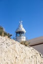 Tower of whitewashed lighthouse behind rock in the natural park Serra Gelada in Albir, Costa Blanca, Spain Royalty Free Stock Photo