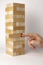 Tower of wooden beams. Finger pushing a wooden beam. Development concept. Jenga board game at home.