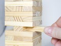 The tower from wooden blocks and man`s hand take one block Royalty Free Stock Photo