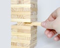 The tower from wooden blocks and man`s hand take one block Royalty Free Stock Photo