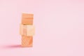 Tower of wooden cubes on a pink background. Childrens toys from natural materials concept zero West. Horizontal frame