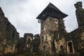 Tower with wooden roof, stone wall and mighty ruins Nevytsky Castle on a cloudy foggy winter day