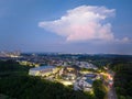Lone towering cloud over bright buildings and suburban development at dusk