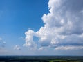 Towering cumulonimbus clouds over green rural landscape with deep blue sky