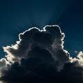 A towering cumulus cloud with distinct, fluffy edges is dramatically backlit by the sun, Royalty Free Stock Photo