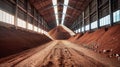 A towering mound of rich dirt dominates the warehouse floor, awaiting its transformation into essential potash fertilizers